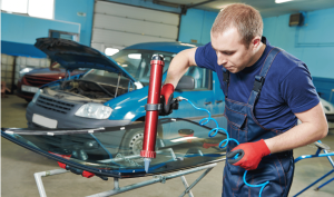 A man applies adhesive to a car for a windshield scratch repair using a specialized tool with professional auto glass repair skill,